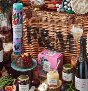 basket with Fortnum & Mason logo printed on it with products from the hamper displayed around it