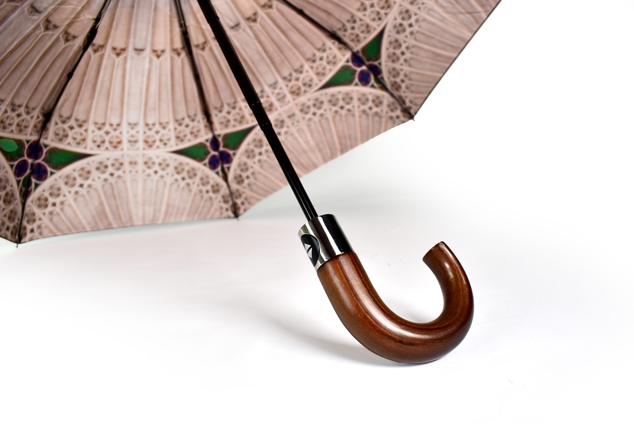 stained glass window printed on inside of umbrella with black pole of umbrella showing and polished dark wood handle