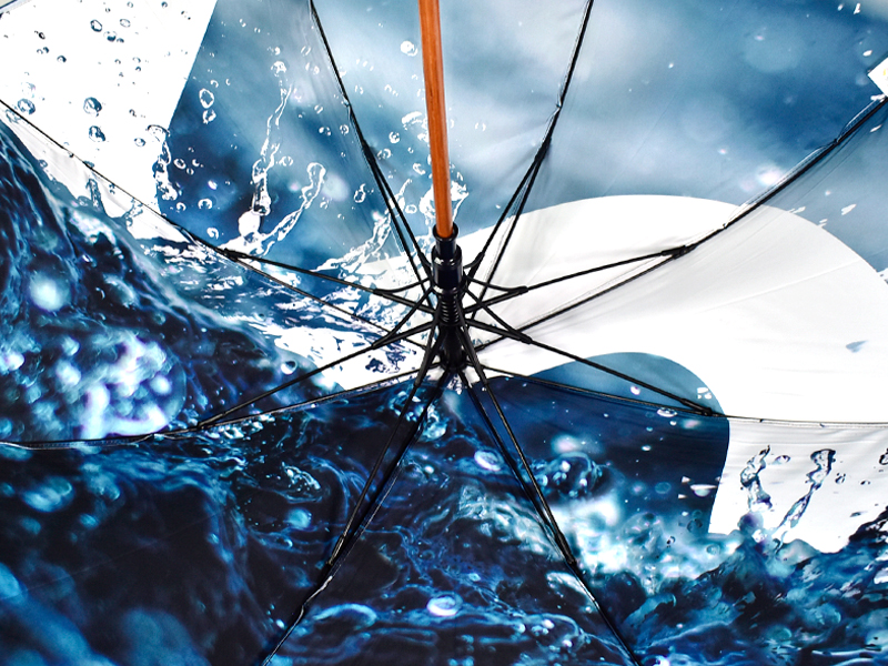 water splash print on inside panel of umbrella with black ribs and wooden pole