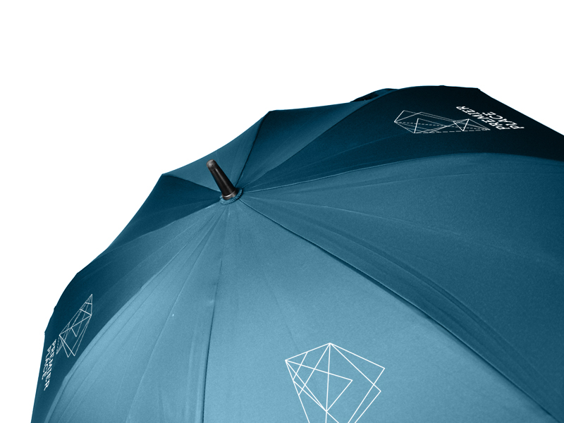 black tip of folding umbrella and blue panels of umbrella